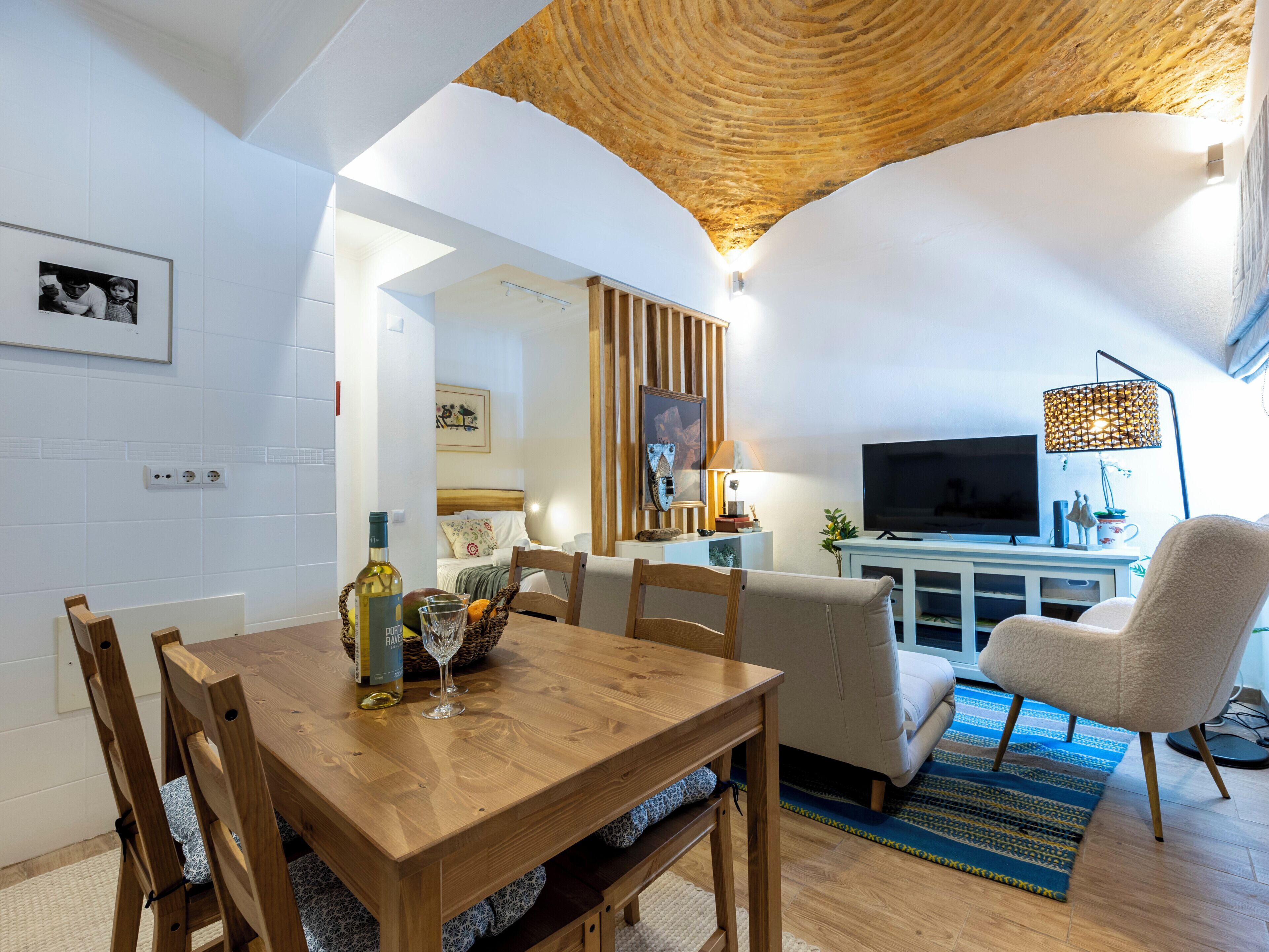 A cozy living room with a wooden dining table, a sofa, and a TV.