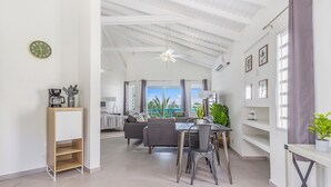 A spacious living area with a dining table, grey sofa, and a view of the outdoors.