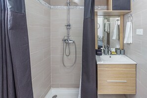 Een moderne badkamer met een douche, een wastafel en een spiegel.