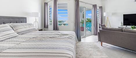 A spacious bedroom with a large bed, a sofa, and a TV.