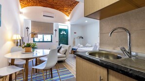 A compact kitchen with a sink, wooden cabinets, and a dining area with chairs and a table. - Casa da Guida Olhão Portugal (Olhão)