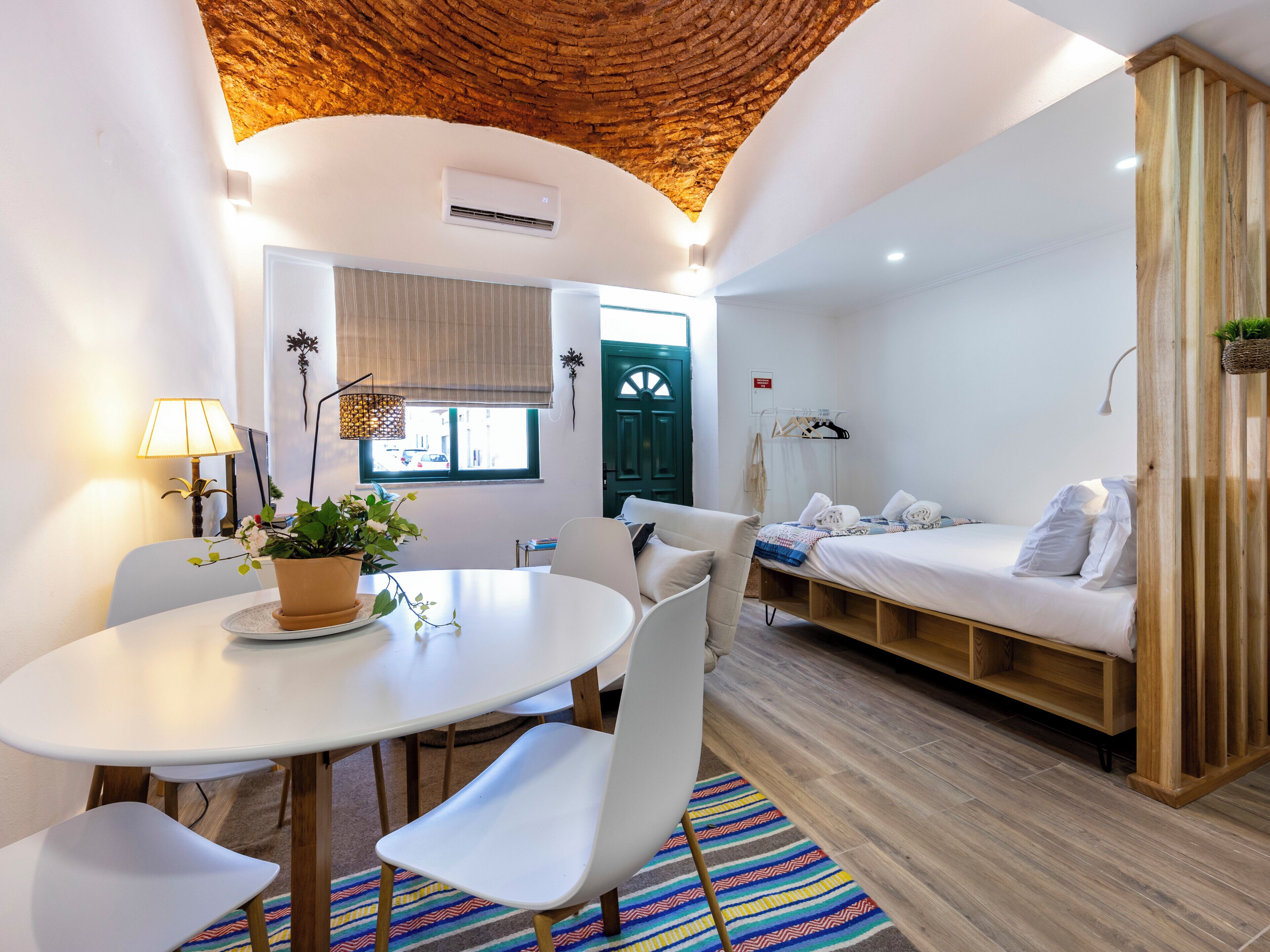 A modern room with a round table, white chairs, a sofa, and a bed.
