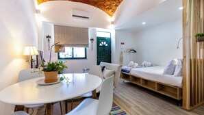A modern room with a round table, white chairs, a sofa, and a bed. - Casa da Guida Olhão Portugal (Olhão)