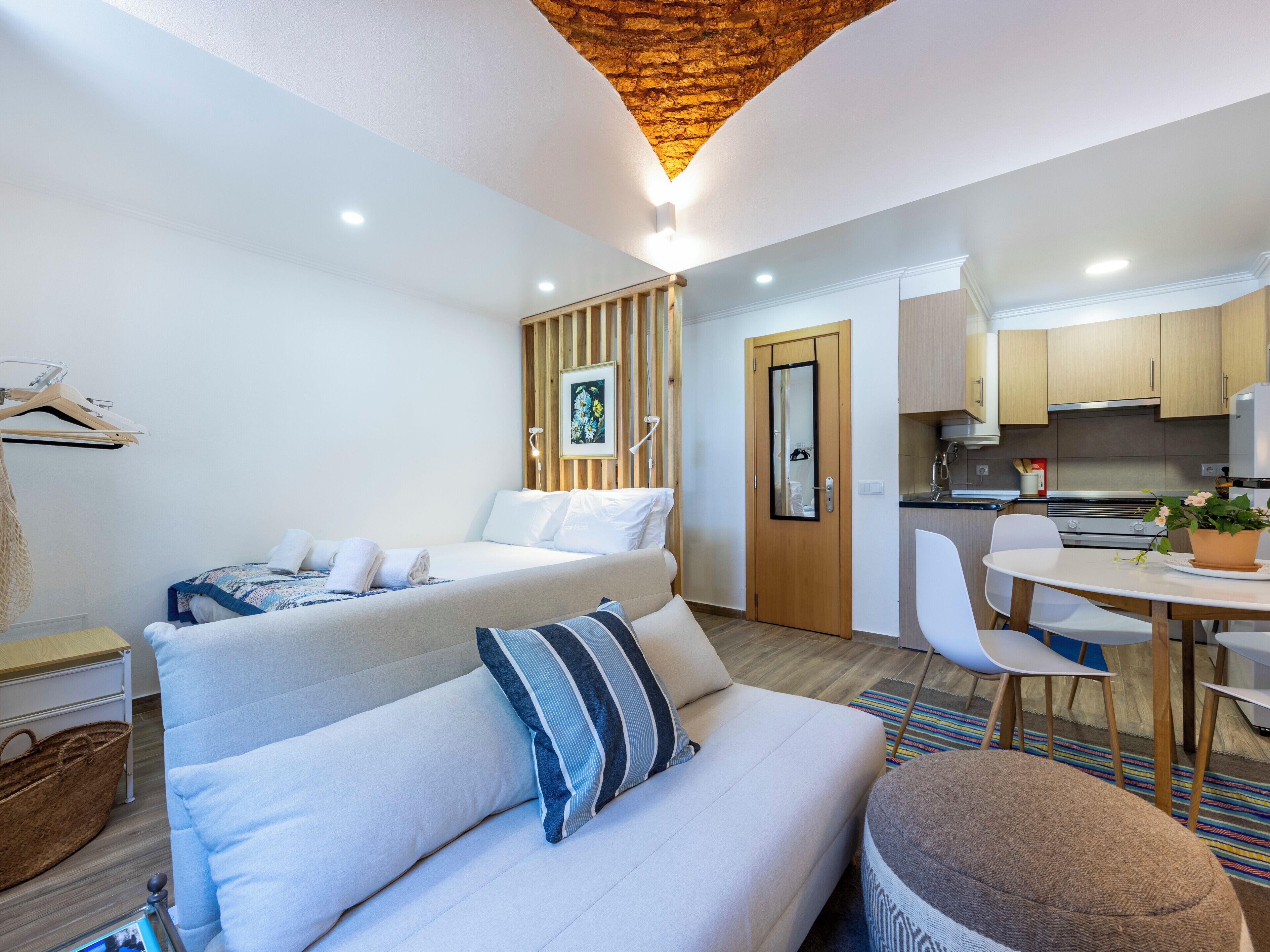Ein modernes Hotelzimmer mit Bett, Sofa, Esstisch und Küchenzeile.