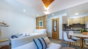 A modern hotel room with a bed, a sofa, a dining table, and a kitchen area. - Casa da Guida Olhão Portugal (Olhão)