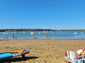 Une plage avec plusieurs bateaux, un poste de surveillance des sauveteurs et des gens qui profitent de l’eau.