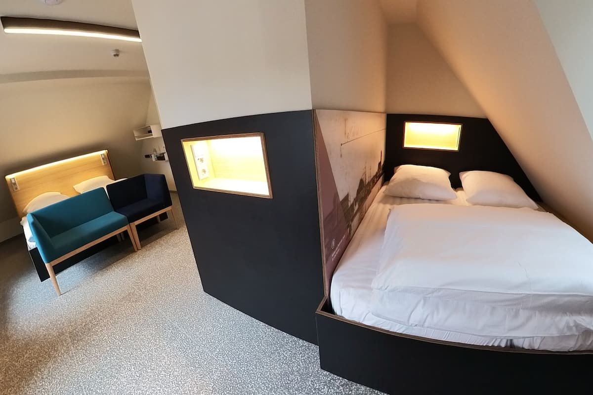A modern hotel room with a curved bed, a sofa, and a small table.