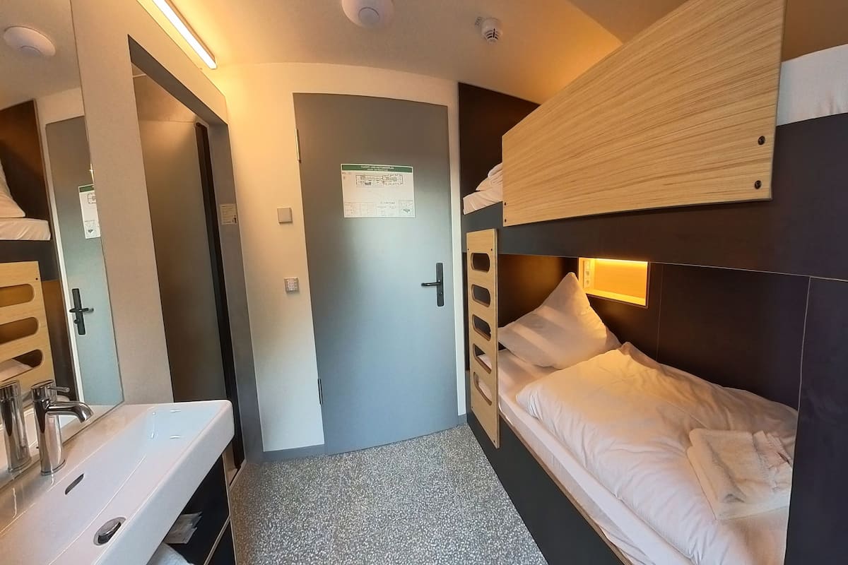 A compact room with a bunk bed, a sink, and a door with a sign.