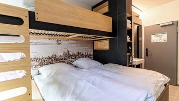 A bunk bed with a cityscape mural, a wooden headboard, and a built-in shelf with towels.