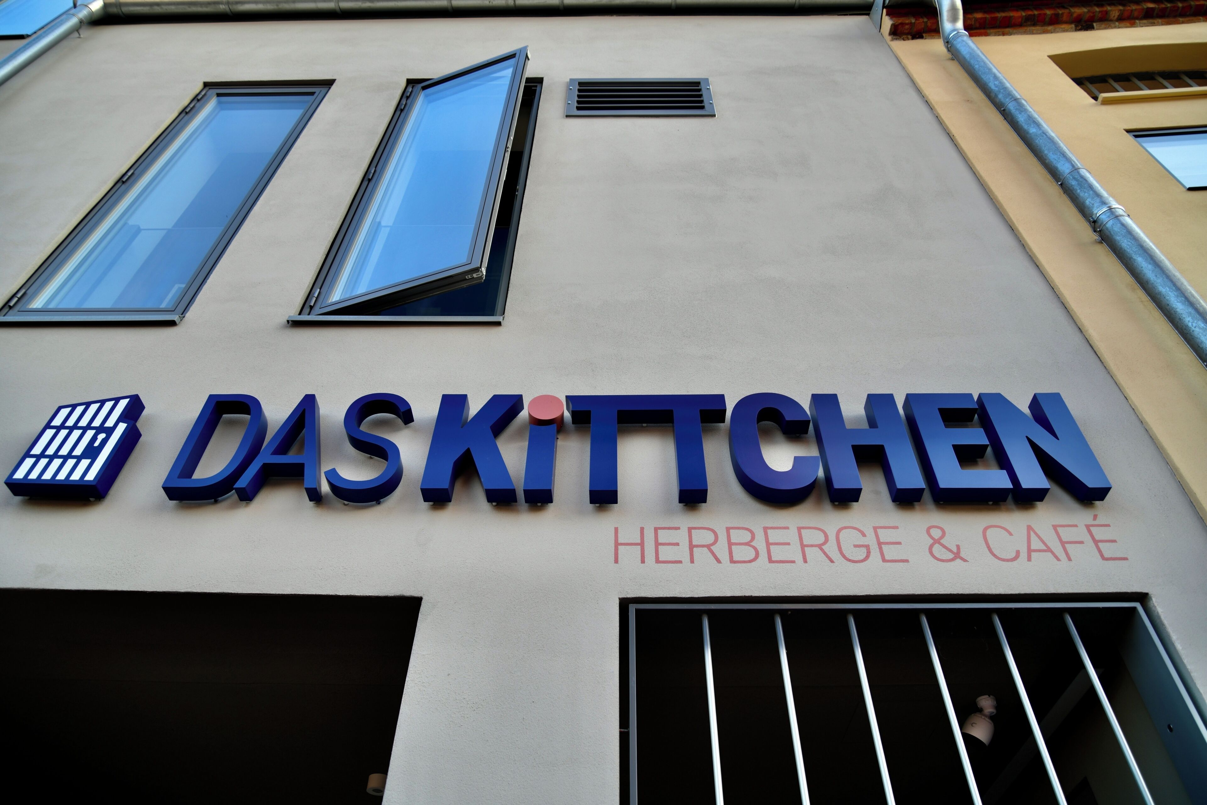 A building with a sign that reads 'DAS KITTCHEN HERBERGE & CAFÉ'.