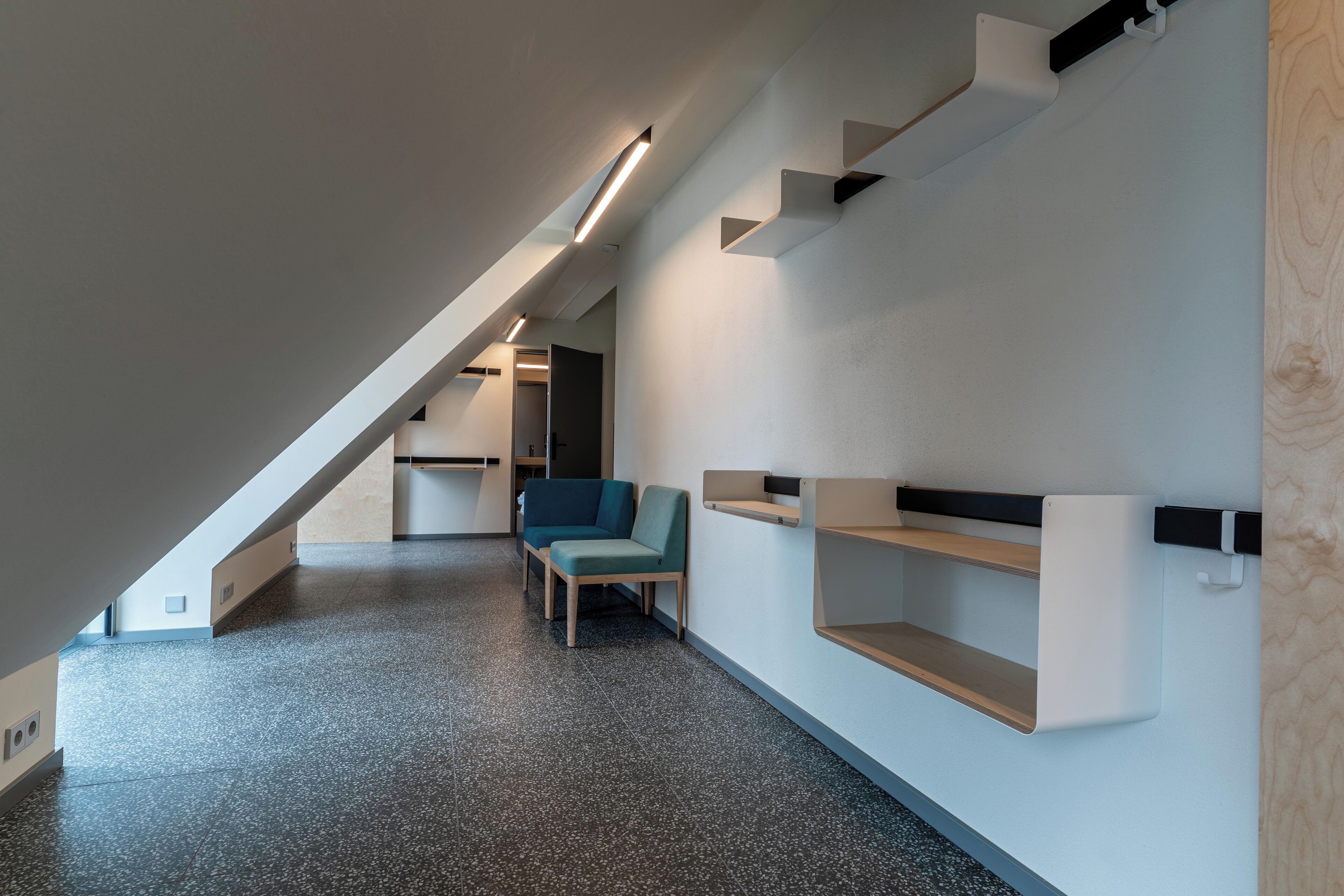 A modern interior with a sloped ceiling, built-in shelves, and a seating area.