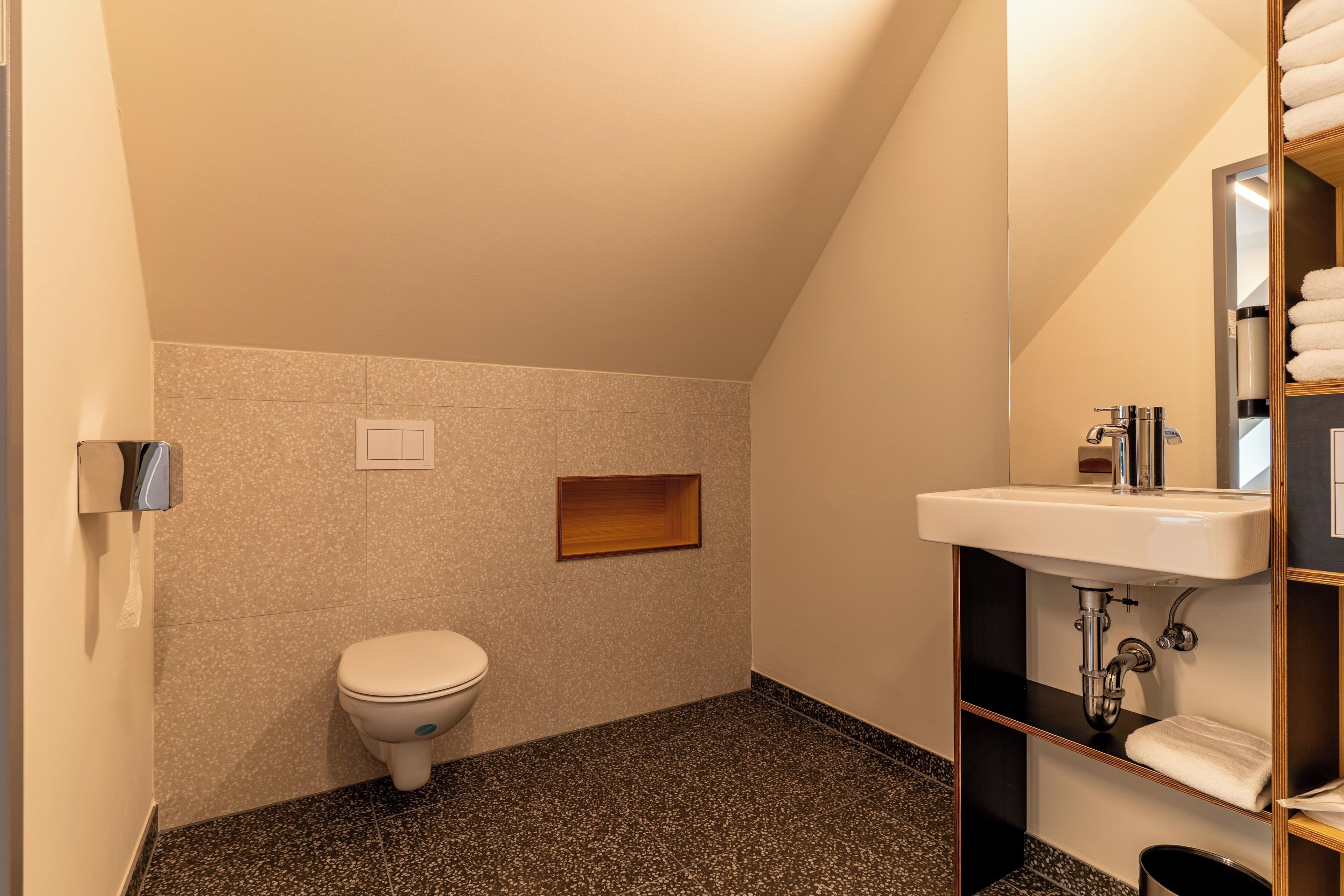 Et stilfuldt, moderne badeværelse med toilet, håndvask og spejl.