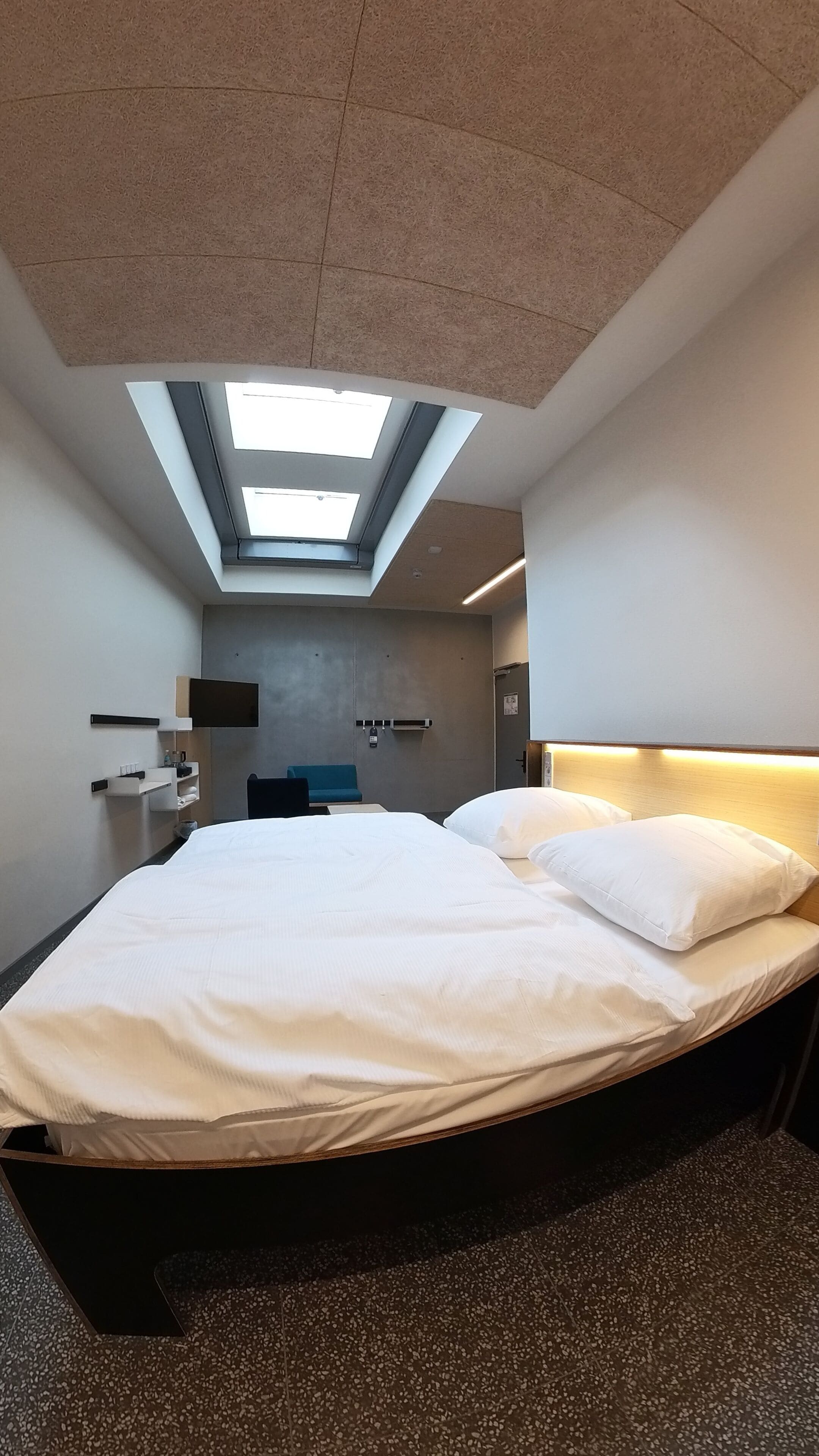 Una habitación de hotel moderna con tragaluz, cama, escritorio y zona de estar.