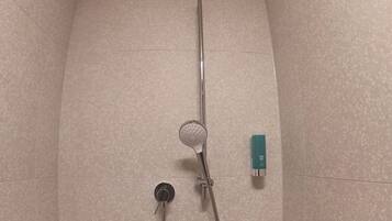 Una ducha con cabezal de ducha manual, grifo empotrado y dispensador de jabón.