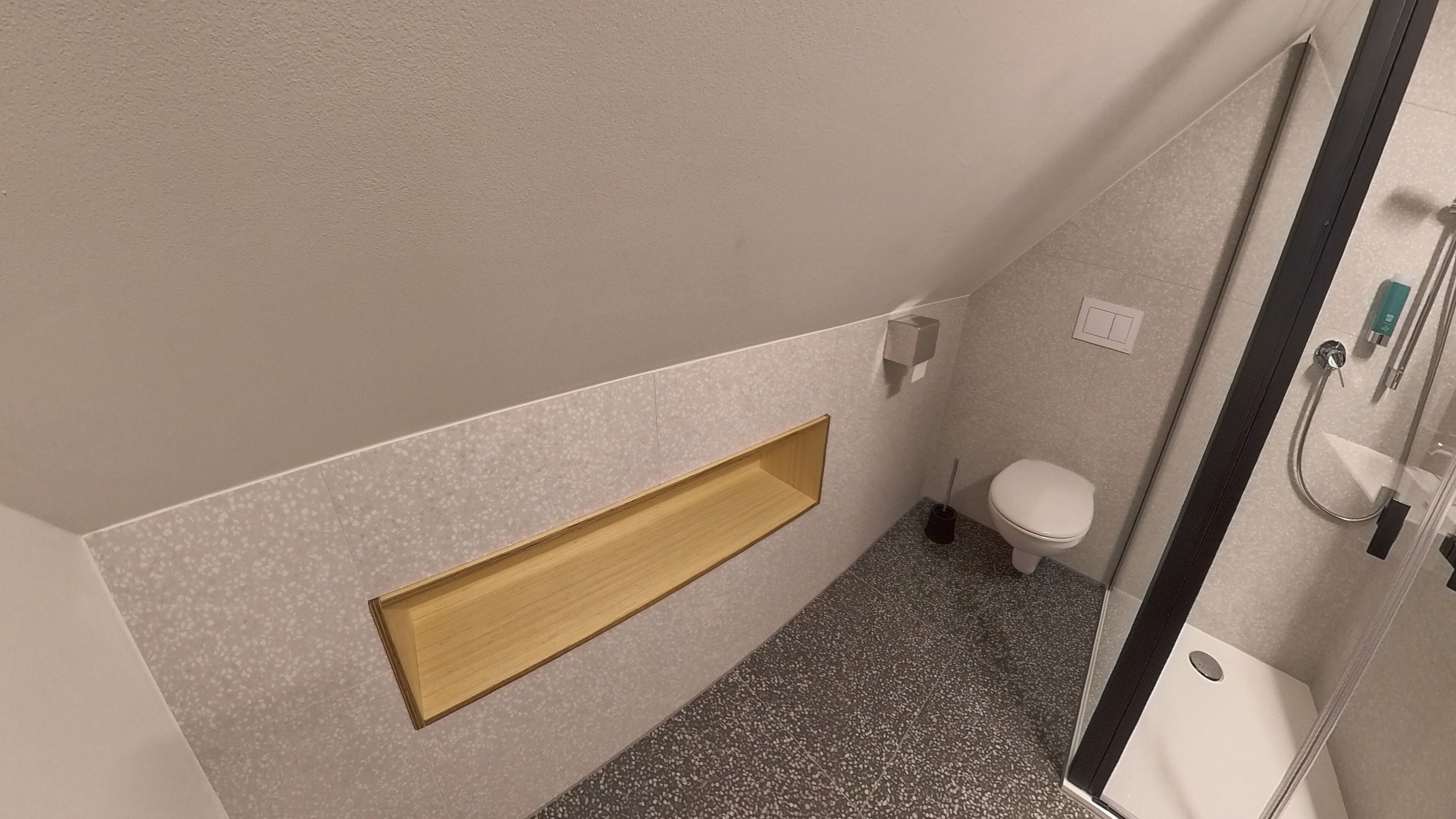 Un baño pequeño con inodoro, ducha y estante de madera.