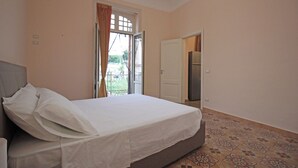 A bedroom with a bed, a door, and a patterned floor. - Moro Central Apartment by Wonderful Italy (Cefalù)