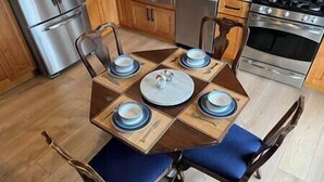 Une table à manger avec quatre chaises, chacune agrémentée d’un coussin bleu, préparée pour un repas à quatre.