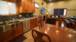 A kitchen with wooden cabinets, a stainless steel sink, and a dining area with a wooden table and chairs. - Fieldstone Manor Estate (Frankfort)