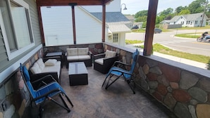 A covered porch with stone walls, a stone bench, and two blue folding chairs. - Fieldstone Manor Estate (Frankfort)