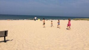 A sandy beach with a few people and a bench. - Elberta Bluffs Cottage (Elberta)