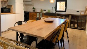 A modern kitchen with a wooden dining table, black chairs, and pendant lights. - Charming Cottage 4* Spa & Activities - Luxury, Comfort & Nature near Futuroscope (Celle-Lévescault)