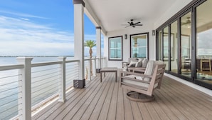 A wooden deck with a table and chairs, overlooking a body of water. - Dolphin Cove-Luxury Sound front retreat w/private pier.  6 bed/6.5 bath sleeps 1 (Navarre)