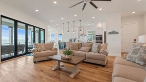 A spacious living room with a large window, a ceiling fan, and a view of the water. - Dolphin Cove-Luxury Sound front retreat w/private pier.  6 bed/6.5 bath sleeps 1 (Navarre)