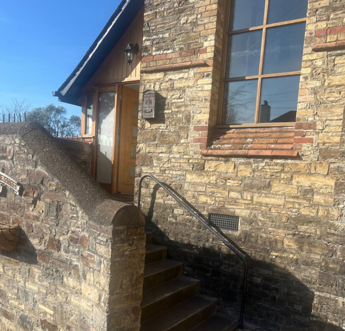 Un bâtiment en pierre avec une porte en bois et une fenêtre dotée d’une rambarde en métal.