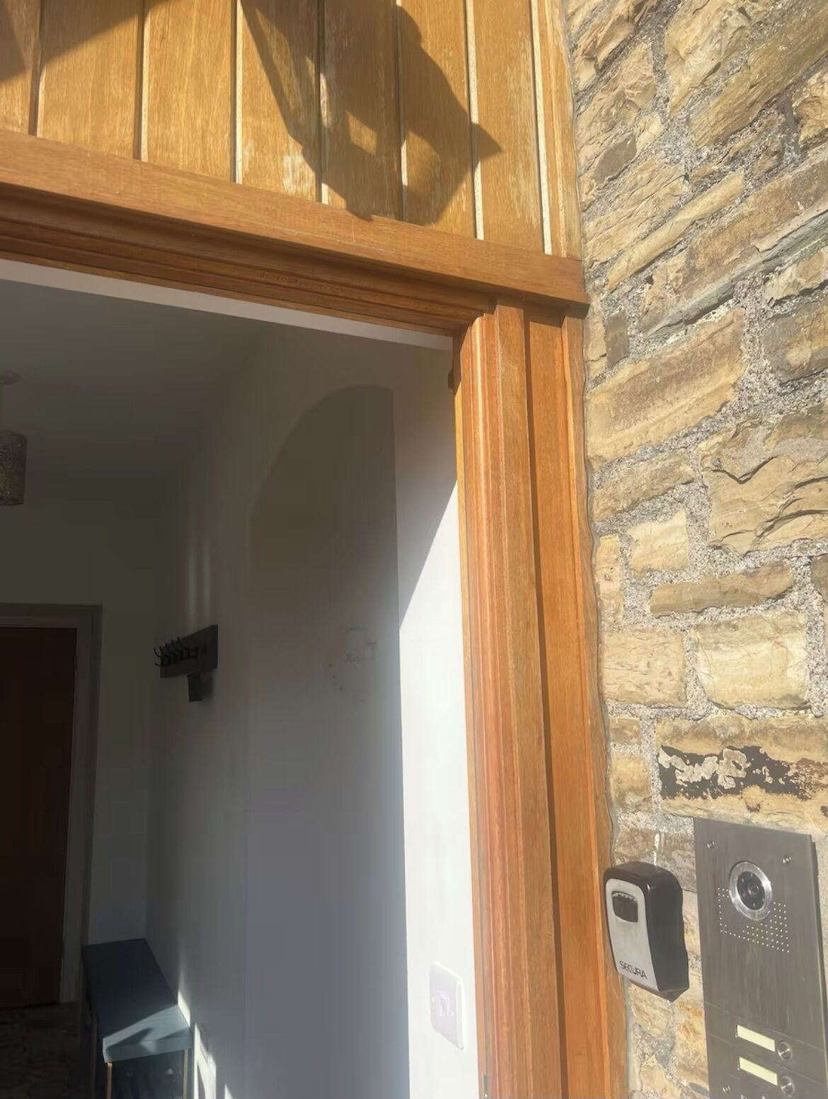 A wooden-framed doorway leading into a room with a stone wall.