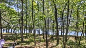 A forested area with a lake, picnic tables, and chairs. - Estrold's Resort-Maple Cabin (St.Germain)