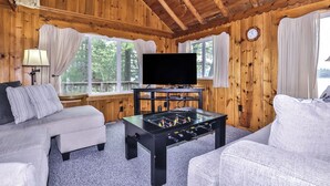 Una habitación acogedora con paredes de madera, un sofá, una mesa de centro con mesa de fútbol y un televisor.