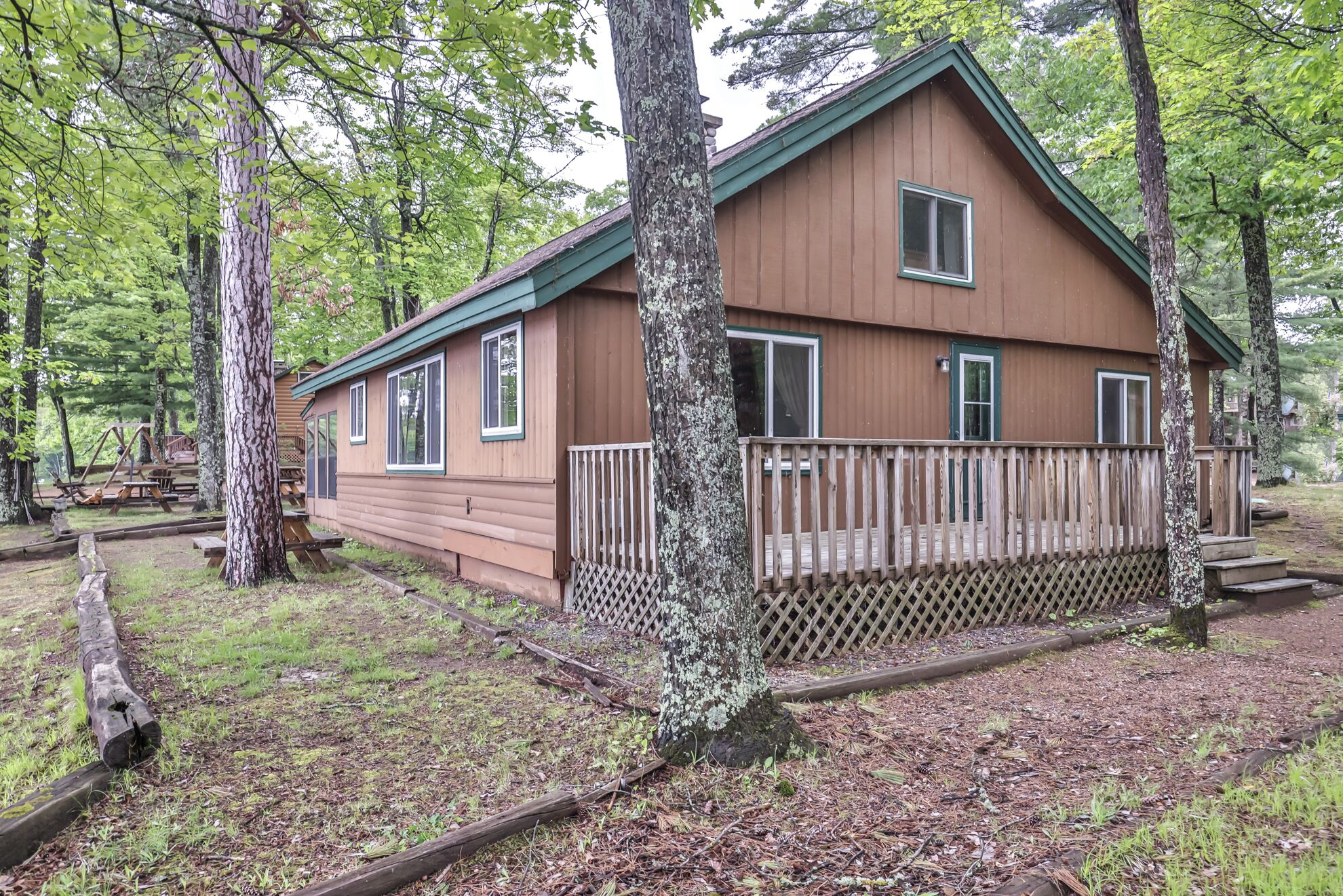 A cabin with a wooden deck, surrounded by trees.