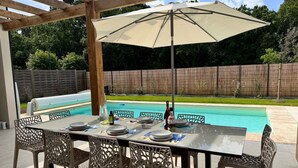 An outdoor dining area with a pool in the background. - Villa 11 by Avecoeur (Saint-Augustin)
