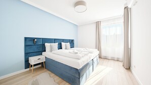 A modern bedroom with a blue headboard, white bedding, and a small bedside table. - Apartamenty Sun & Snow Villa Verona (Mielno)