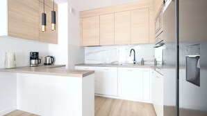 A modern kitchen with white cabinets, a marble backsplash, and stainless steel appliances. - Apartamenty Sun & Snow Villa Verona (Mielno)