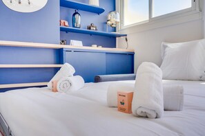 Relax in a spacious room with a large bed, white linens, and a shelf for personal touches.