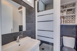 Bathroom features a sleek sink, large mirror, and shower area with glass door.