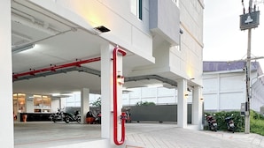 En modern byggnad med ett takförsett parkeringsområde, betonggolv och synliga konstruktionselement som rör och räcken.
