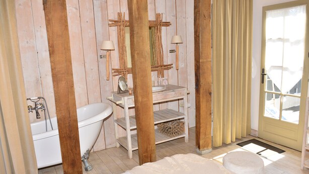 A rustic bathroom with a wooden vanity, a white bathtub, and a large mirror. - Chambres D'hôte A LA Villa DU Grand Large (Biscarrosse)