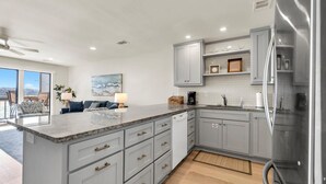 A modern kitchen with grey cabinets, a large island, and stainless steel appliances. - Boardwalk 284- Lakefront Resort Living! Short Walk to Beach! Prime Location! (Miramar Beach)
