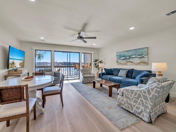 A spacious living room with a large dining table, a blue sofa, and a ceiling fan.