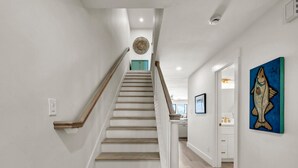A staircase with wooden steps and white railings leading to a room with a kitchen and a bathroom. - Boardwalk 284- Lakefront Resort Living! Short Walk to Beach! Prime Location! (Miramar Beach)