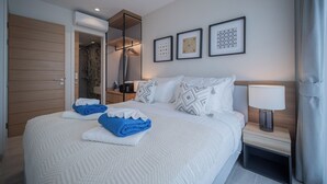 A hotel room with a bed, a nightstand, a lamp, and a wardrobe. - Lakeside Residences by NLA (Choeng Thale)