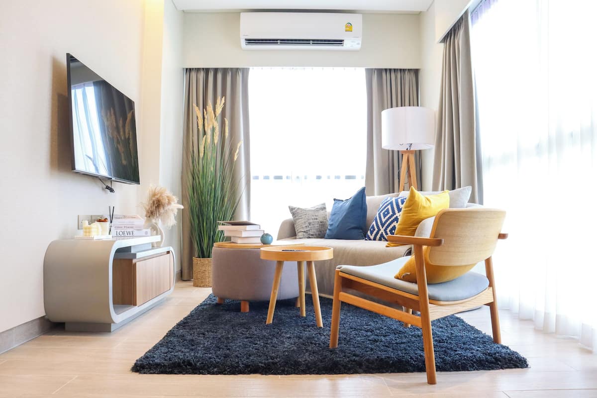 A modern living room with a sofa, armchair, and coffee table, a flat-screen TV, and a sideboard.