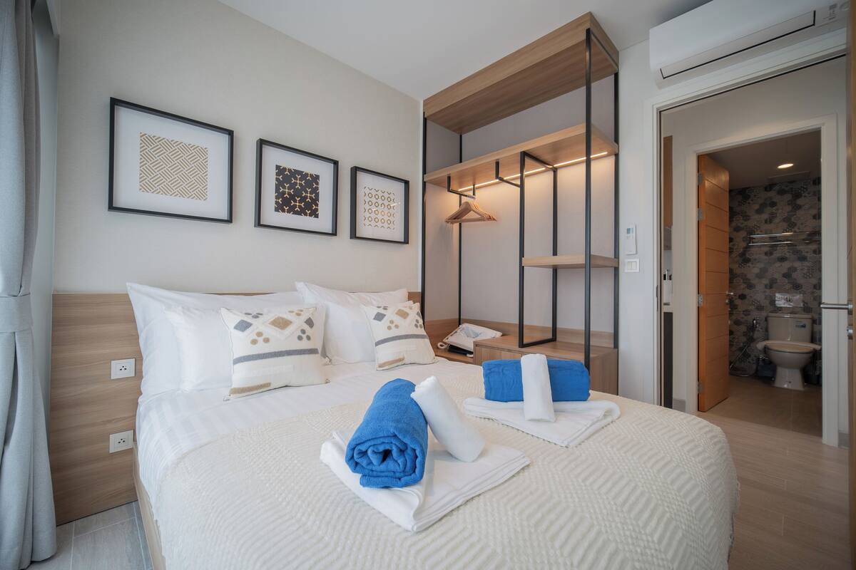A hotel room with a bed, a bedside table, a mirror, and a wardrobe.