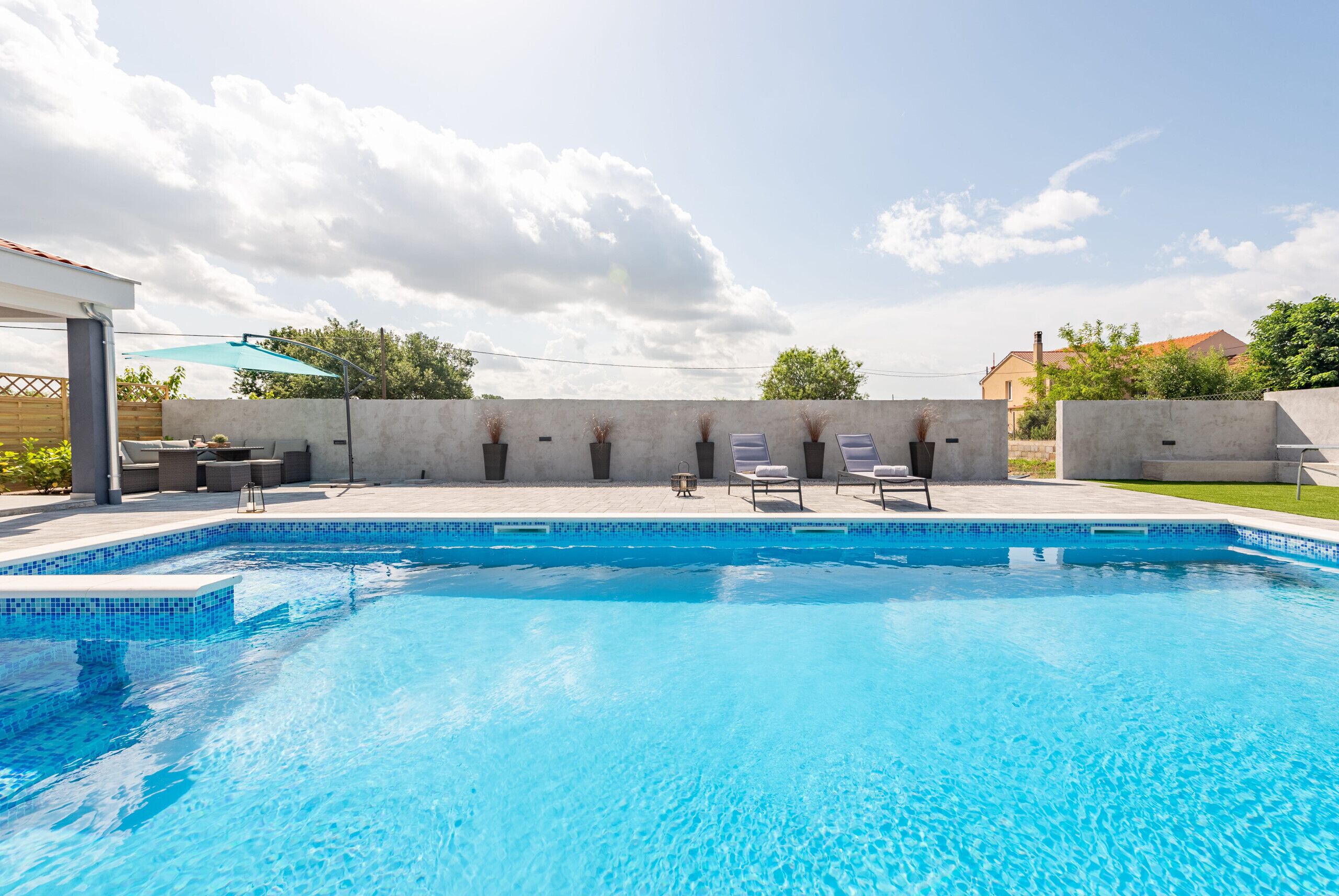 Une piscine avec des chaises longues et une pergola.
