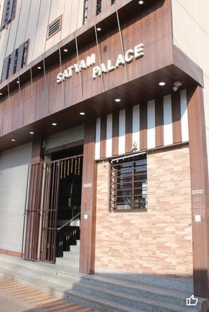 Exterior del Palacio Satyam con diseño moderno, destacando una entrada imponente con una reja de metal y una escalera que conduce a la entrada principal.