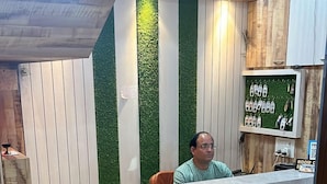 A reception area with a marble counter, a green wall with vertical stripes, and a wooden ceiling. - Hotel Satyam Palace (Nokha)