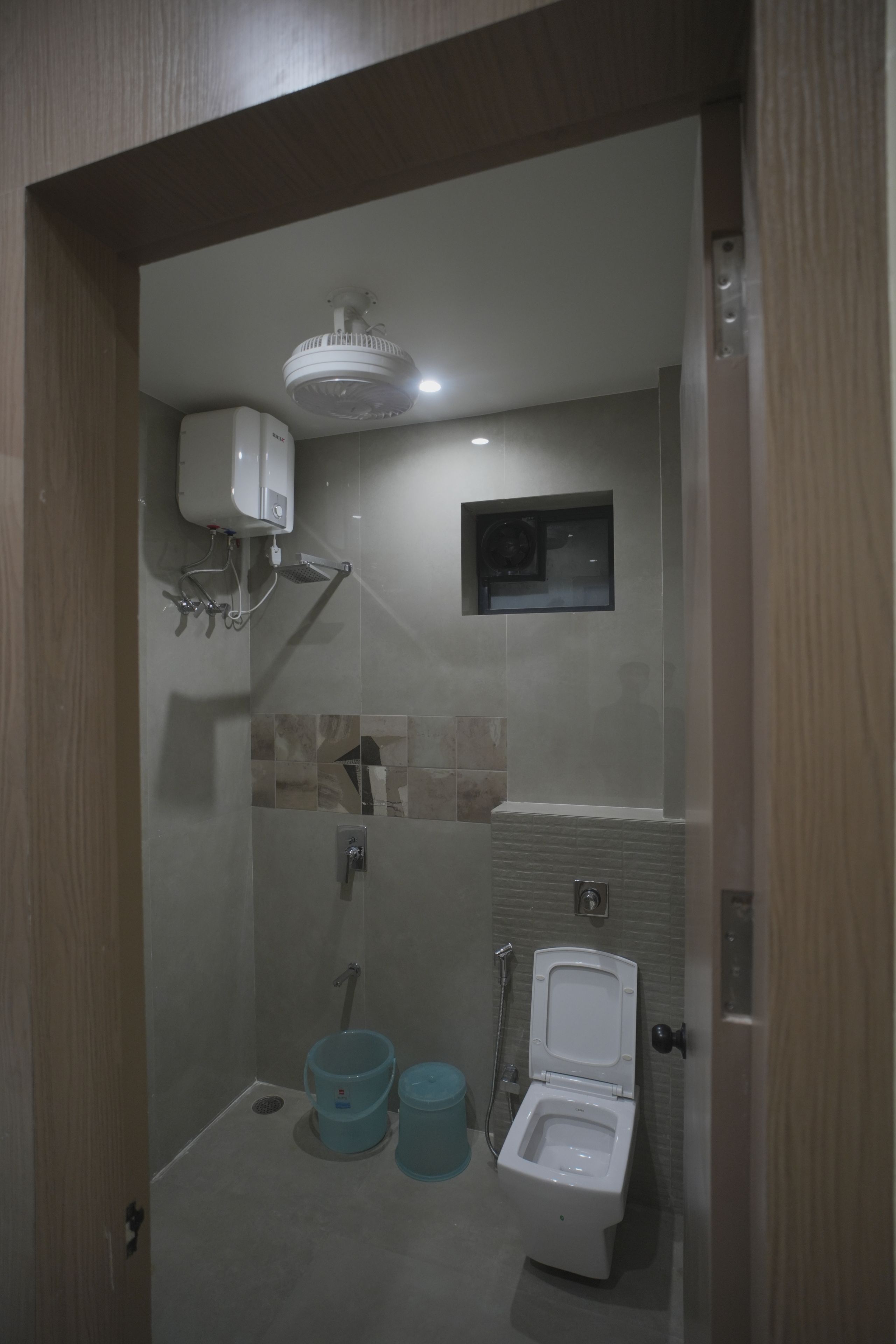 A bathroom with a shower, toilet, and a ceiling fan.
