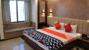 A hotel room with a large bed, a bench, a mirror, and two wall-mounted lights. - Hotel Satyam Palace (Nokha)